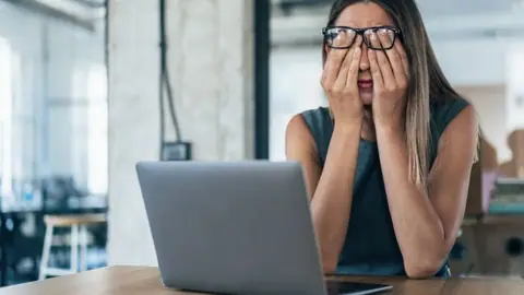Zmęczona kobieta przy laptopie w biurze